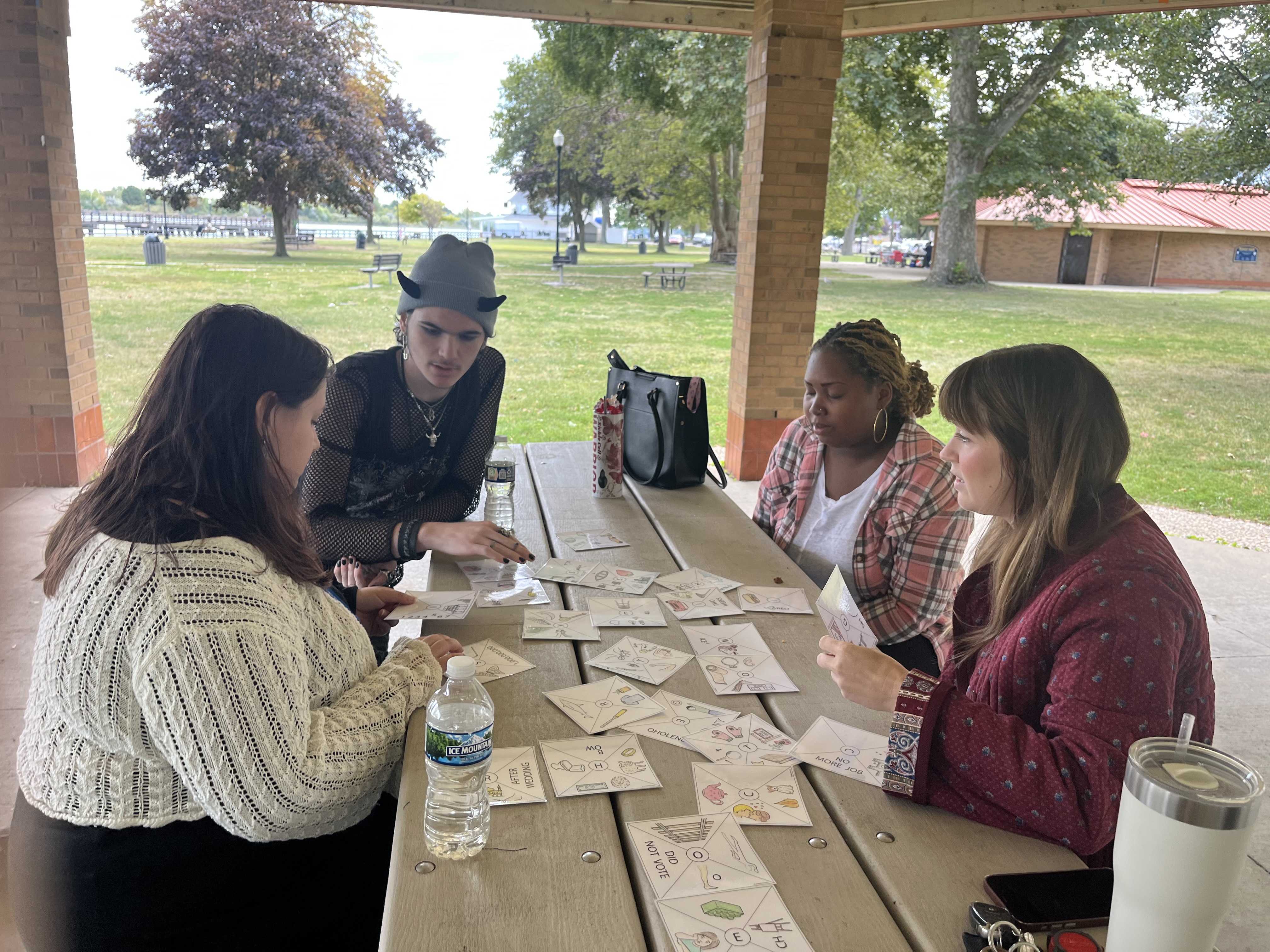 Four team members working together around a picnic table in an outdoor park pavilion